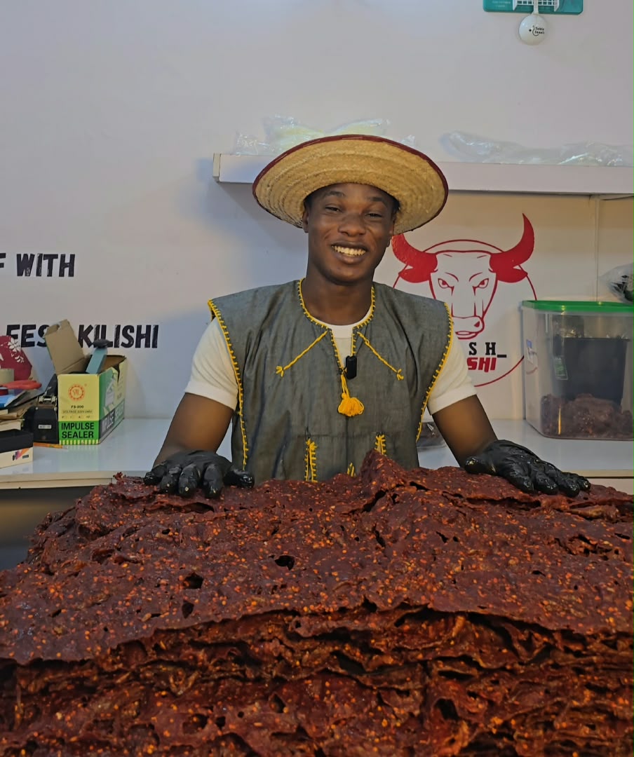 Founder Feshitan smiling behind a large stack of Kilishi sheets